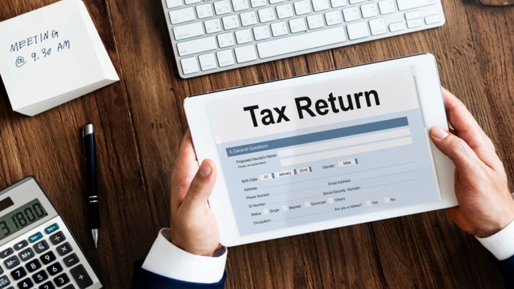 A tax advisor in Singapore reviewing corporate income tax returns and financial statements at a professional desk